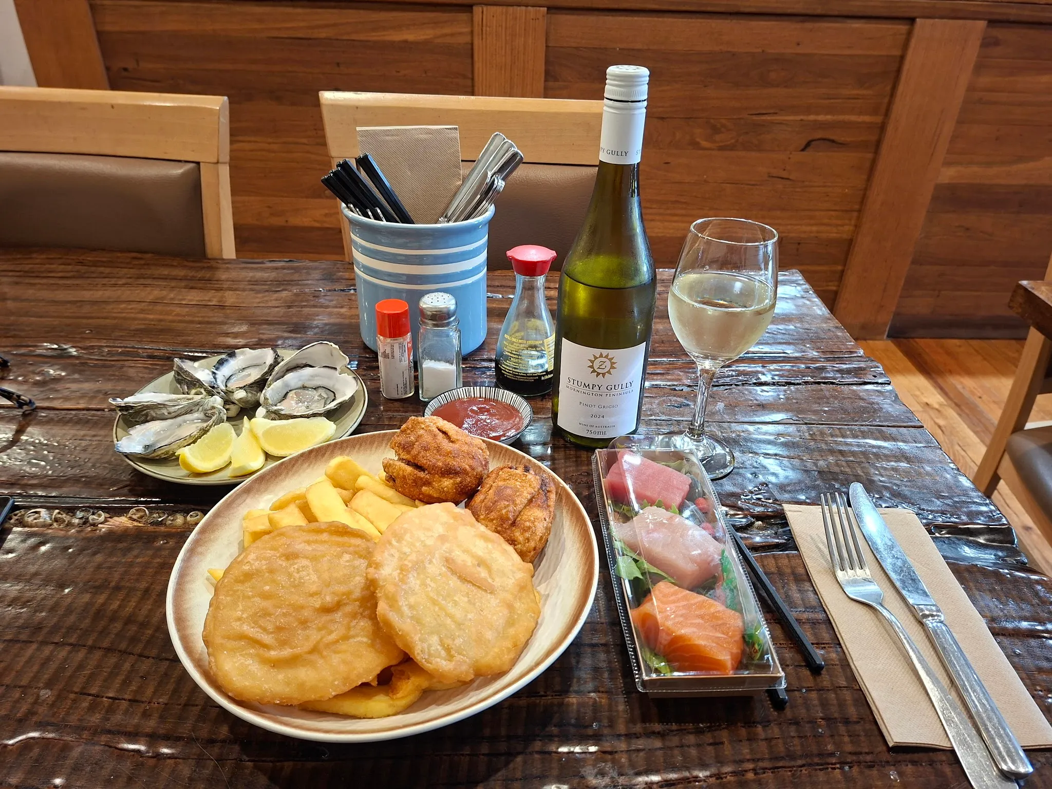 A lifestyle table spread at Blue Fin with oysters, wine glasses, and coastal seafood dishes