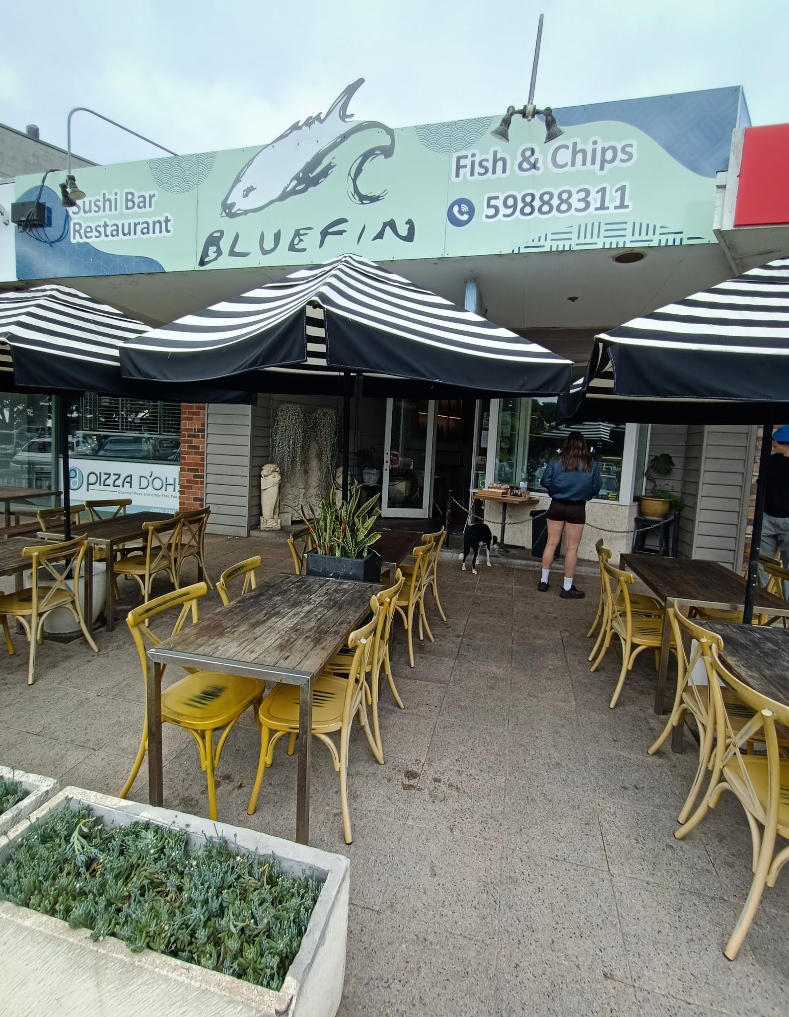 Blue Fin Blairgowrie exterior with striped umbrellas, yellow outdoor chairs and teal signage