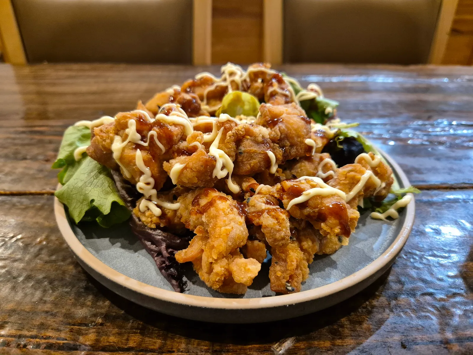 Karaage fried chicken with teriyaki sauce and kewpie mayo drizzle on grey ceramic plate