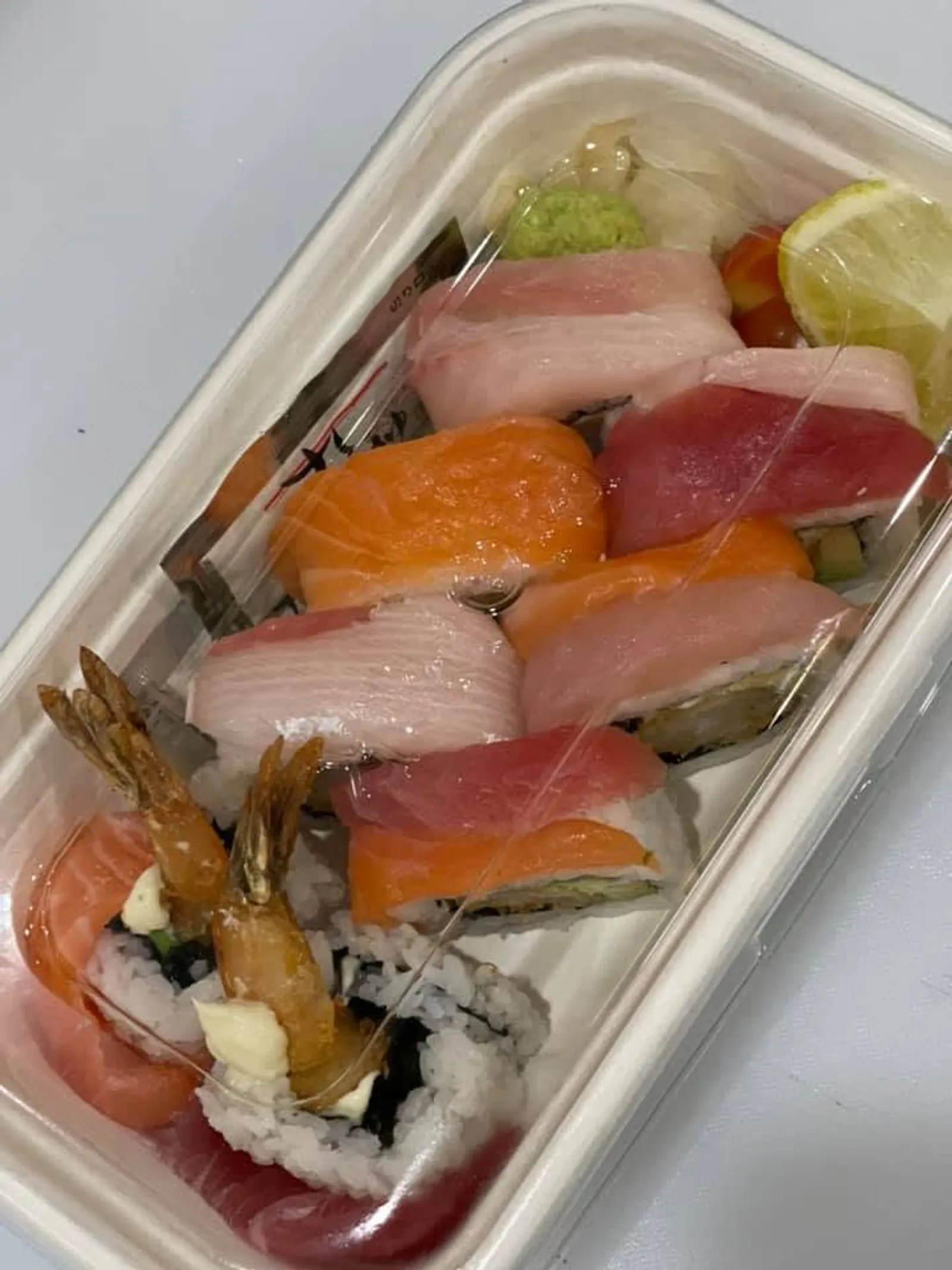 Takeaway sushi combo box with prawn nigiri, assorted sashimi and rolls